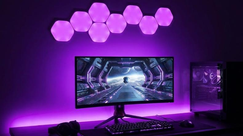 Setup gaming con retroiluminación LED Govee detrás del monitor y paneles luminosos hexagonales en la pared sincronizados en color morado.