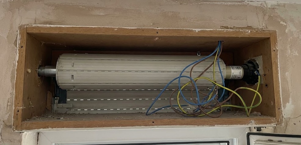 Cableado del motor de persiana para domotización Interior de una caja de persiana abierta mostrando el motor tubular y los cables de conexión eléctrica