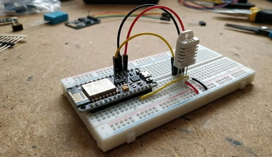 Primer plano de un microcontrolador ESP8266 conectado con cables de colores a un sensor de temperatura y humedad DHT22 sobre una breadboard blanca para configuración en ESPHome.