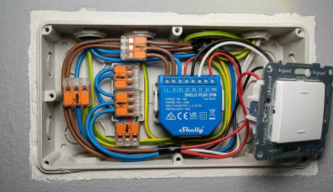 Shelly Plus 2PM instalado dentro de la caja del interruptor de persiana, junto a los cables y bornas Wago